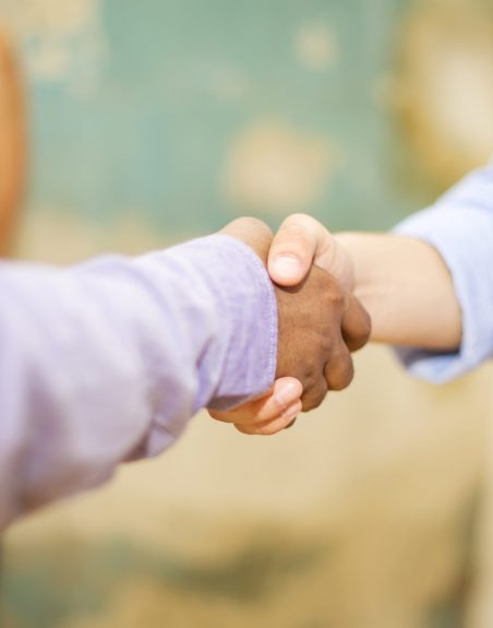 Closeup image of business partners making handshake in grunge office
